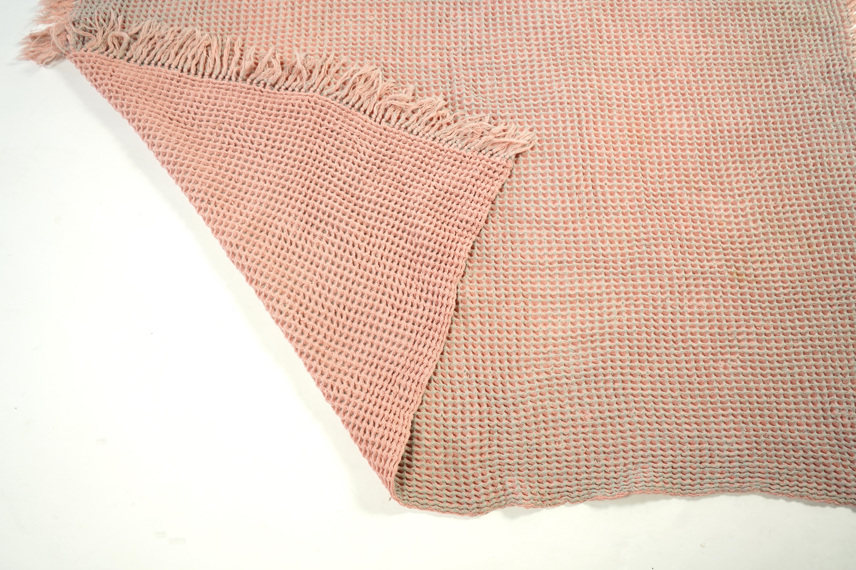 An unusual pink and grey honeycomb woven wool Welsh blanket. 194cm x 176cm. Condition - various threads have pulled and there is a small stain.